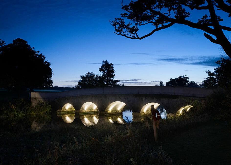 Stone bridge arches lit at night in the grounds of Carton House