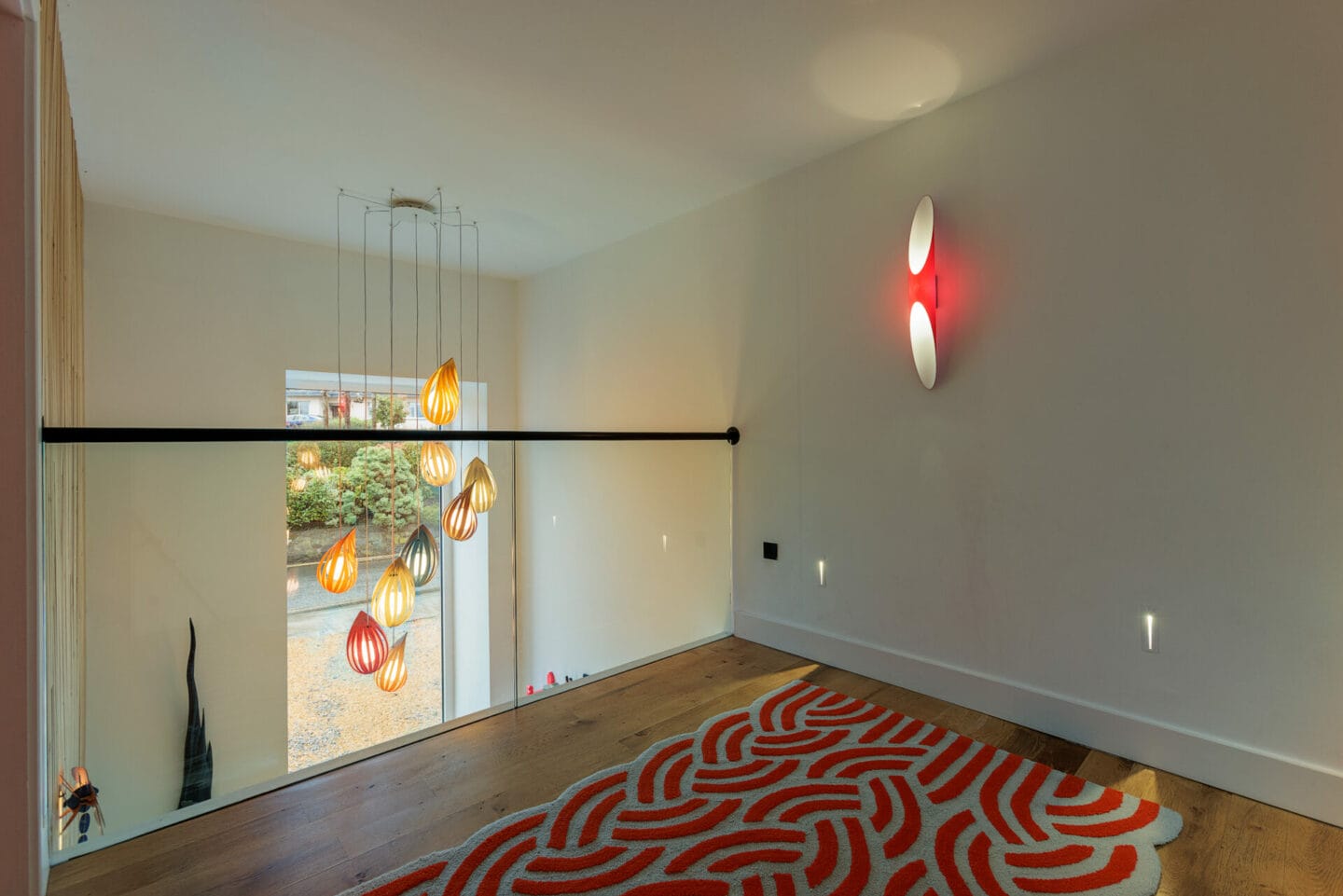 Landing with a cluster of glass pendants and red wall lights, residential lighting by Willie Duggan
