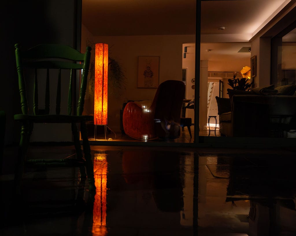 Living room at night lit by a warm floor lamp in a 1950s terrace house